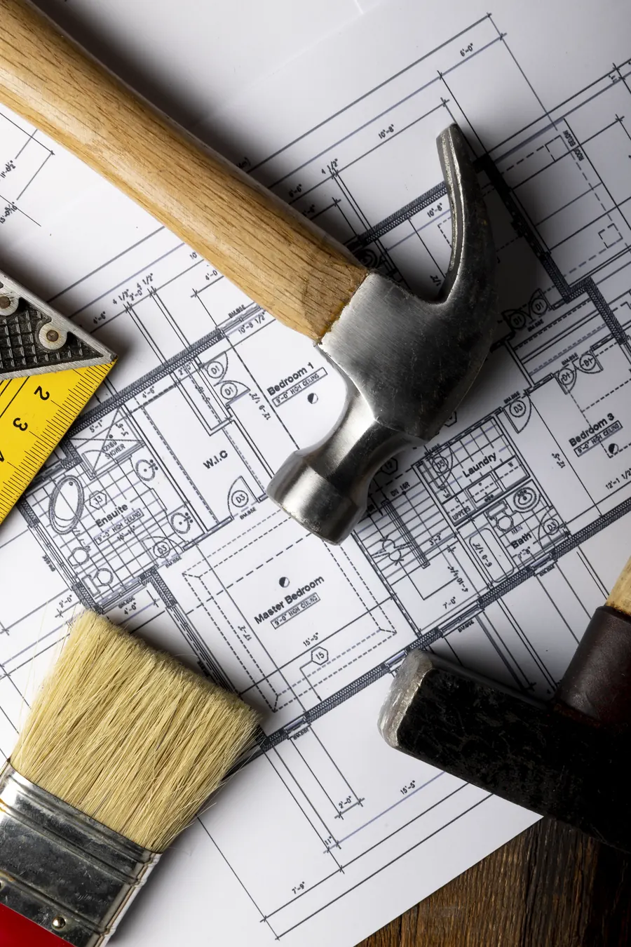 Grundrisspläne mit Hammer, Zollstock und Pinsel auf dem Tisch
